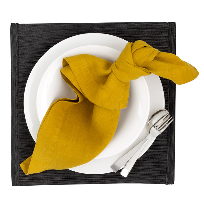 Golden Mustard HG Signature hand-dyed linen napkin, knotted on a white plate with silverware.