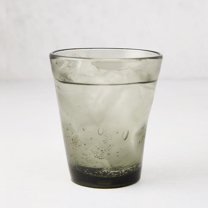 Grey Henri mouth-blown glass, 8 oz, filled with ice and a bubbly drink.