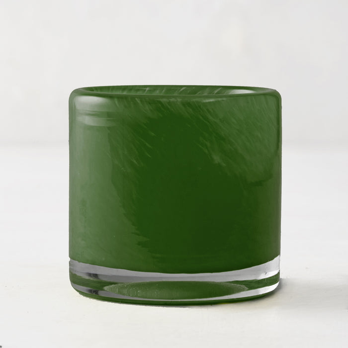 Mouth-blown, hand-formed green votive glass candle holder with clear base.