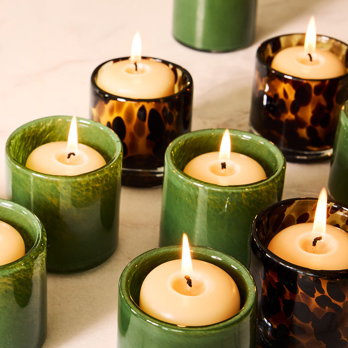 Green and tortoise shell glass votive candle holders with lit candles.