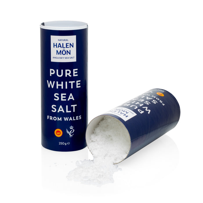 Halen Mon Pure White Sea Salt in a dark blue cylindrical container, with some salt spilled.