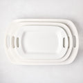 Set of 3 white ceramic serving platters with handles, nested from small to large.