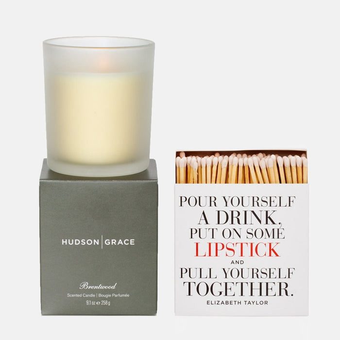 Hudson Grace Brentwood scented candle in frosted glass on a gray box, beside a white matchbox with "Pour Yourself a Drink" text.
