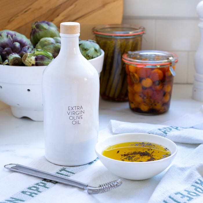 Hudson Grace 16.9oz white ceramic olive oil bottle with black label, wood stopper, and small bowl of oil.