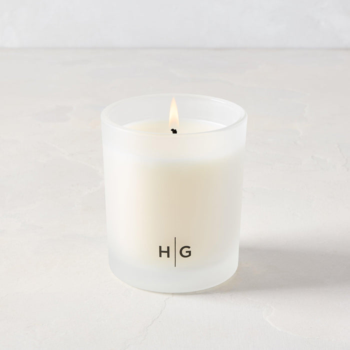 Hudson Grace San Marzano scented candle in a frosted glass vessel with "HG" logo, lit wick.
