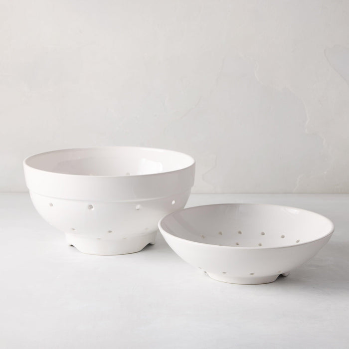 Two white ceramic berry bowls, one large and one small, with drainage holes.