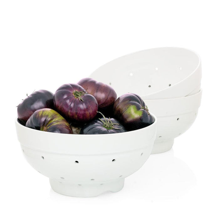 Hudson Grace white ceramic colander, 9.5"Dia, filled with dark heirloom tomatoes. Two more colanders stacked behind.