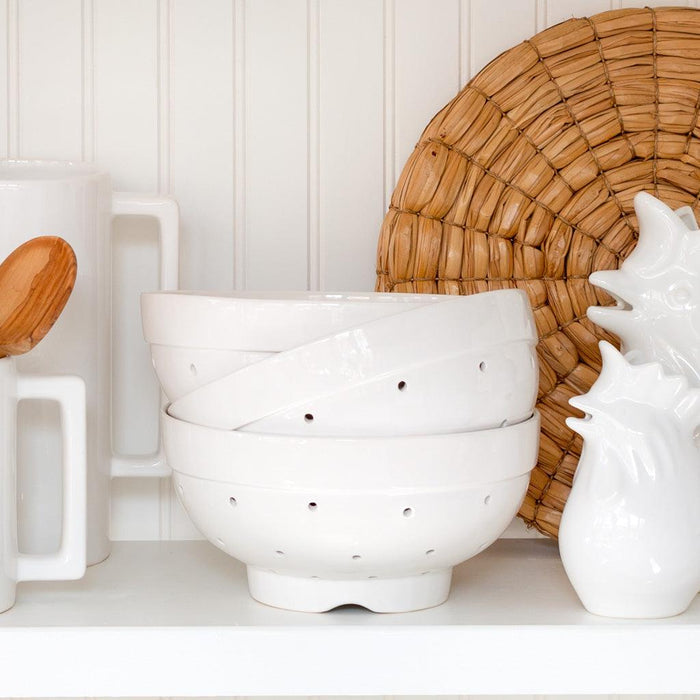 Hudson Grace white ceramic colander, vintage-inspired, with drainage holes, stacked on a white shelf.