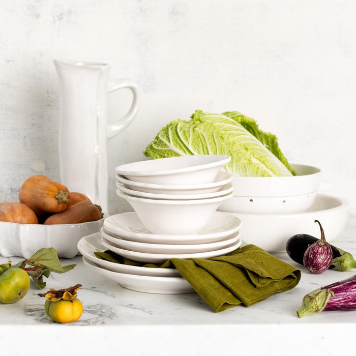 Hudson Grace white ceramic colander with bowls, plates, and fresh vegetables on a marble surface.