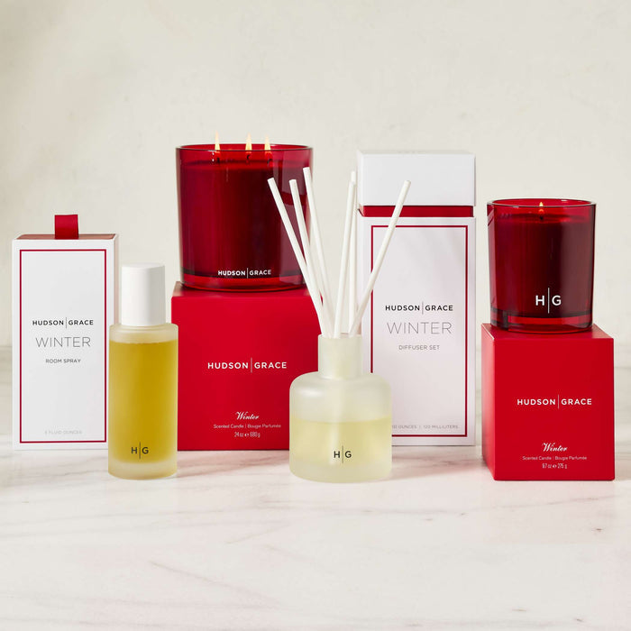 Hudson Grace Winter collection: red glass candles, room spray, and diffuser with white boxes.