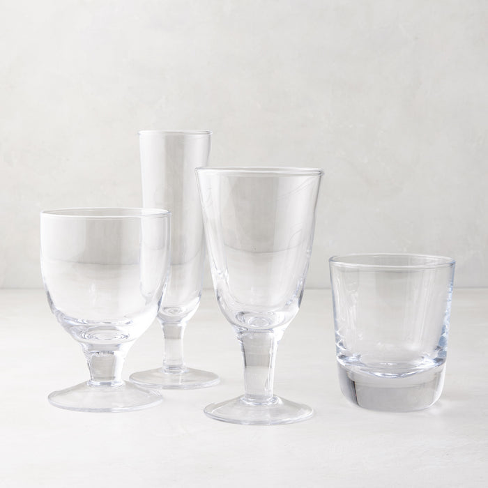 Clear glass stemless and stemmed glasses, including a chunky Hudson glass, on a white surface.