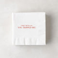 White paper cocktail napkin with "I didn't fall for you, YOU TRIPPED ME!" in red text.