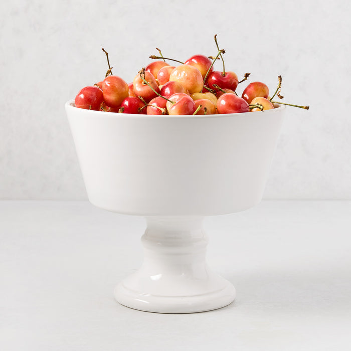 Creamy white Italian ceramic compote, 9" Dia x 8" H, filled with fresh red and yellow cherries.