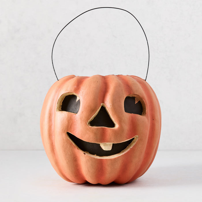 Handcrafted orange papier-mâché Jack O' Lantern candy bucket with distressed finish and wire handle.