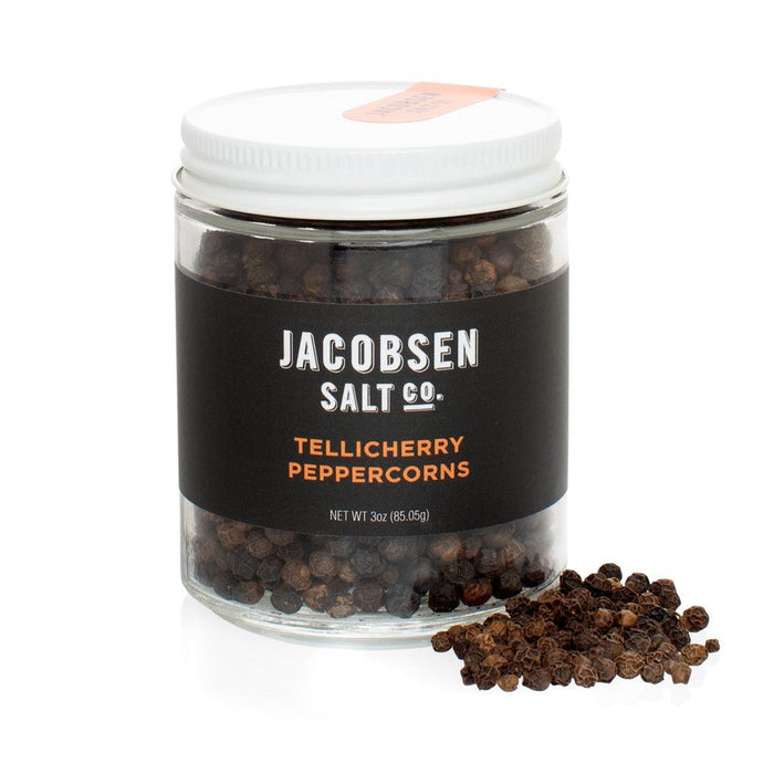 Jacobsen Salt Co. 3 oz. glass jar of black Tellicherry peppercorns with a white lid and black label.