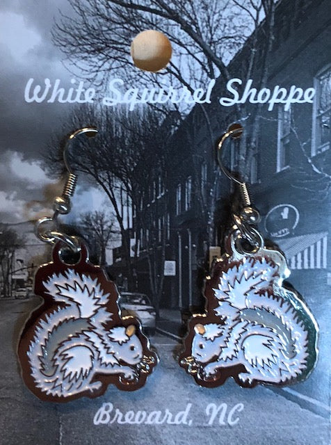 A pair of metal dangly earrings with a white squirrel holding an acorn.