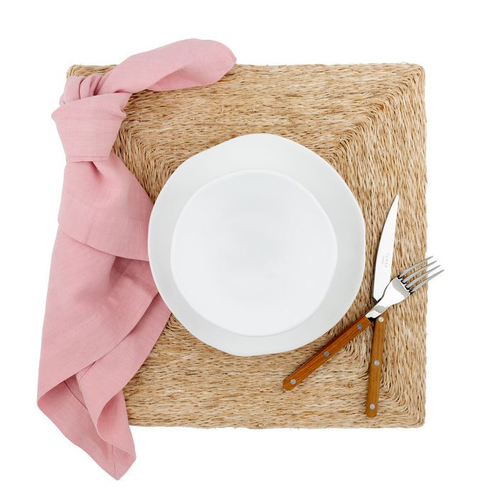 Lanai Natural Abaca Woven Square Placemat, 15" with white plate, pink napkin, and wood-handled cutlery.