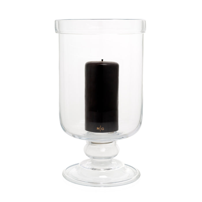 Large clear glass footed chalice hurricane candle holder with a black pillar candle inside.