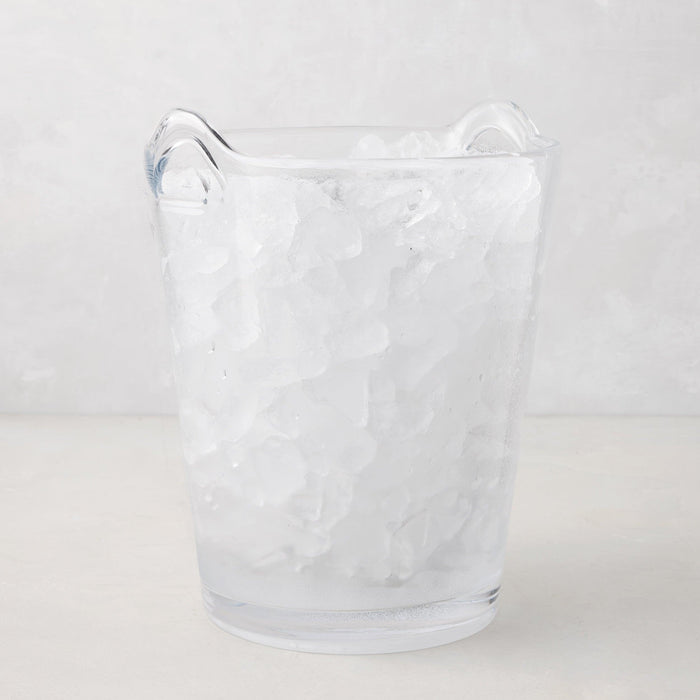Large clear handblown glass ice bucket with two handles, filled with ice.