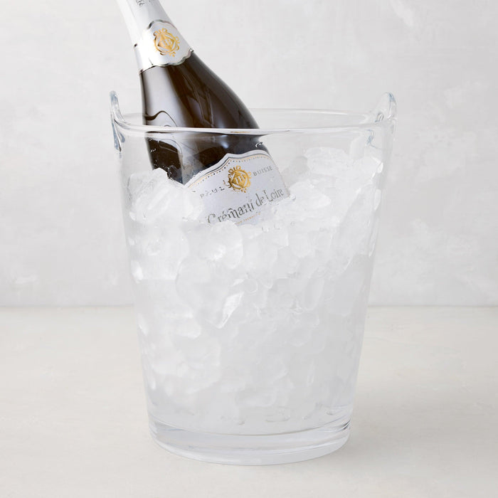 Large clear handblown glass ice bucket with handles, holding a champagne bottle and ice.