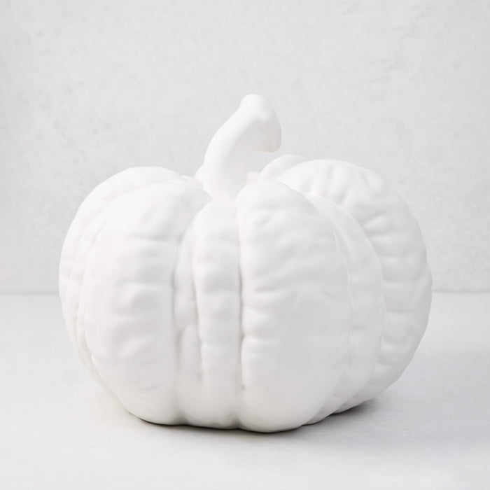 Large matte white ceramic pumpkin, 12"H x 10"Dia, with a short stem and ribbed texture.