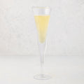 Clear, thick, air-blown glass champagne flute with a rippled rim, filled with sparkling yellow liquid.