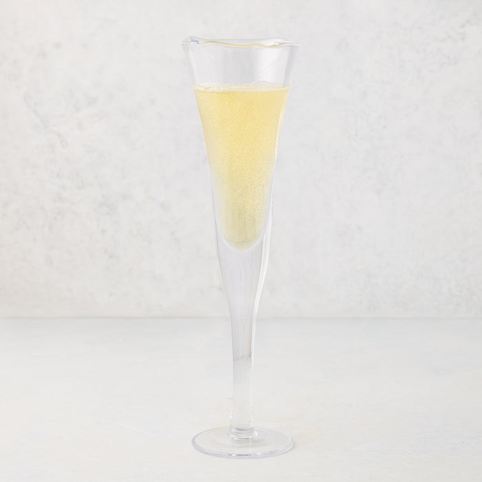 Clear, thick, air-blown glass champagne flute with a rippled rim, filled with sparkling yellow liquid.