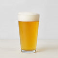 Clear, thick-walled Hudson Grace glass filled with golden beer and white foam.