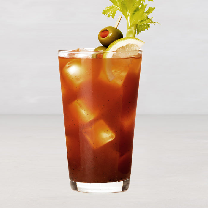 Tall, clear glass filled with a Bloody Mary, ice, celery, green olive, and lemon slice.
