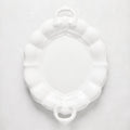 White oval ceramic serving platter with scalloped edges and handles.