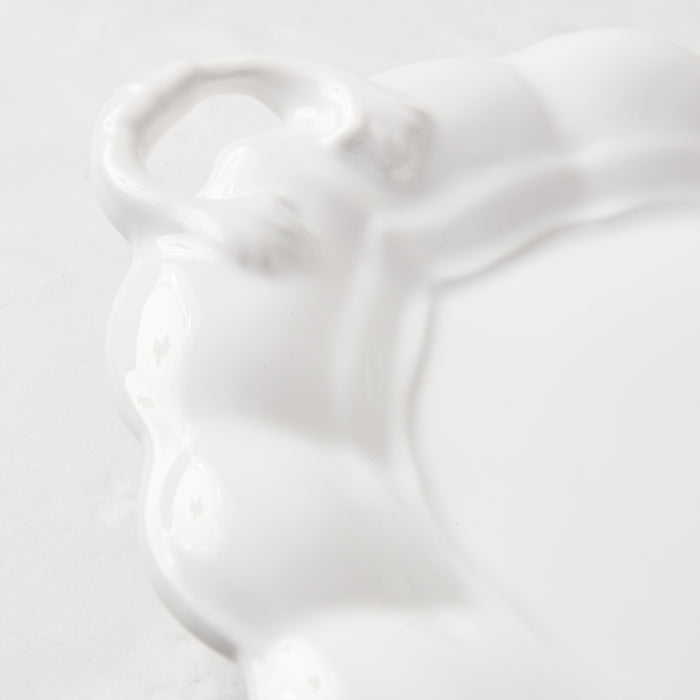 White ceramic oval serving platter with decorative handles and French detailing.