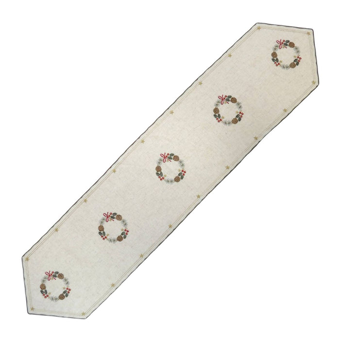 Long linen table runner with embroidered Christmas wreath motifs, pinecones, and berries on natural fabric