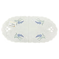 Oval white linen table runner with blue delphinium floral embroidery, scalloped edges, and cutwork detailing
