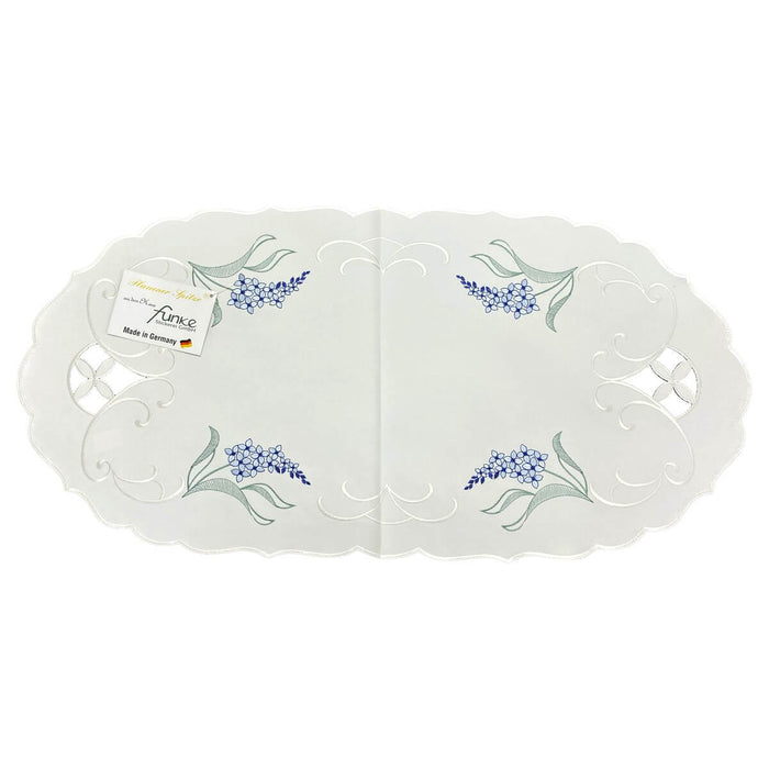 Oval white linen table runner with blue delphinium floral embroidery, scalloped edges, and cutwork detailing