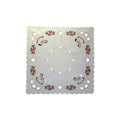 A square cream tablecloth with scalloped edges featuring a floral pattern with rocking horses, crystals, apples, and holly, displayed on a plain background.