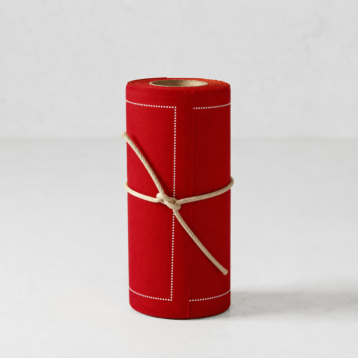 Roll of 50 lipstick red cotton cocktail napkins with white dotted border, tied with twine.
