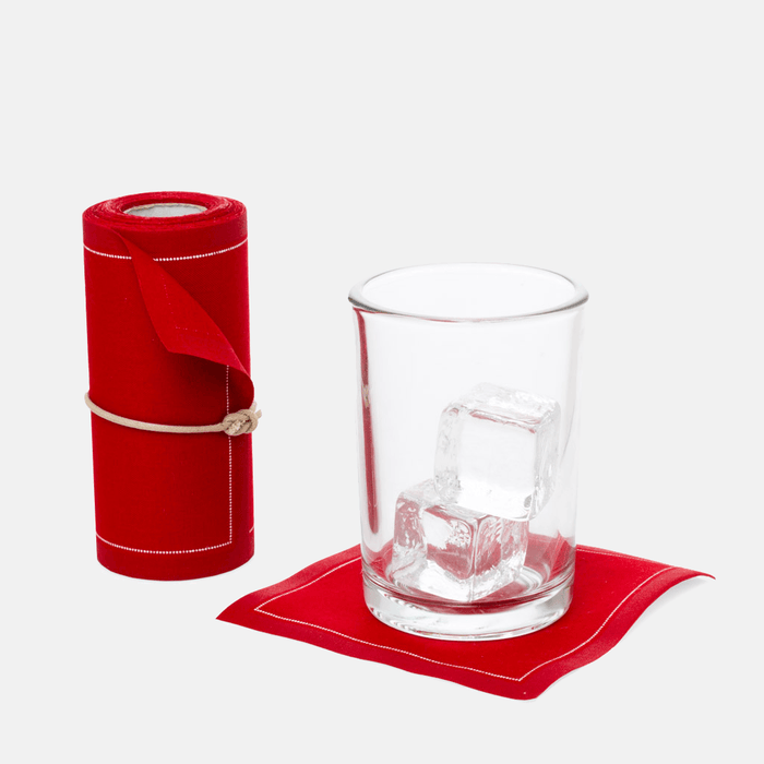 Roll of 50 Lipstick Red cotton tear-off cocktail napkins with a glass of ice on one napkin.