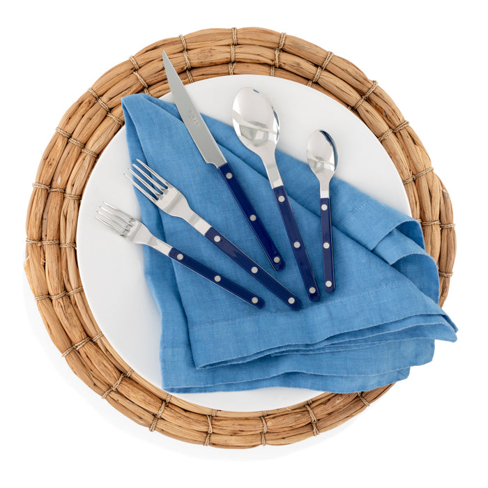 Lupine Blue HG Signature hand-dyed linen napkin on a white plate with blue-handled silverware.