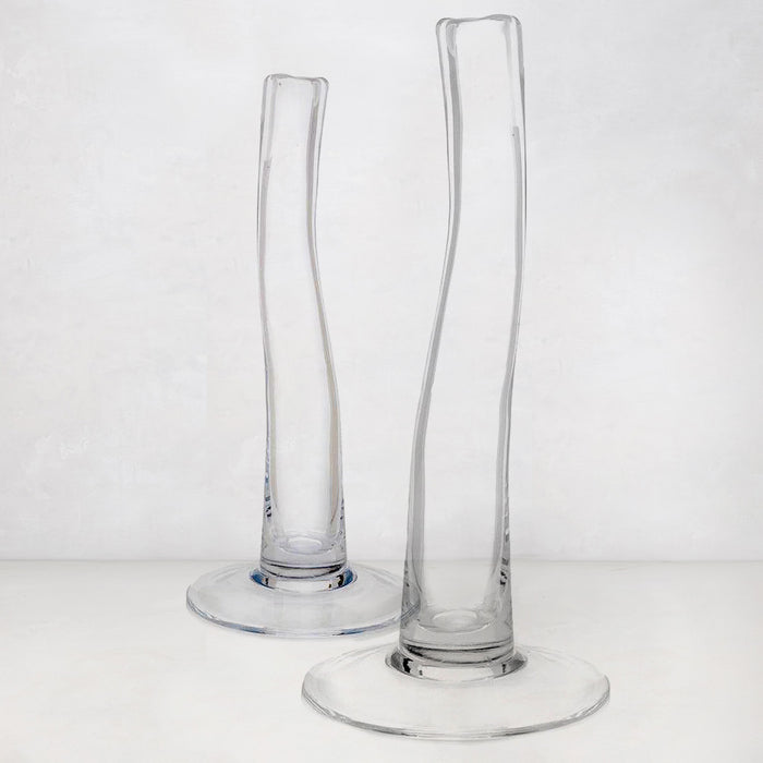 Two clear, tall, slender glass vases with scissor-cut mouths and wide bases.