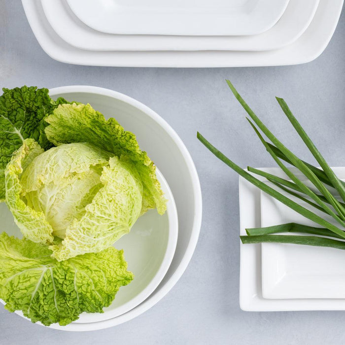 White HG Modern Large Ceramic Serve Bowl with green cabbage, next to white rectangular plates and chives.
