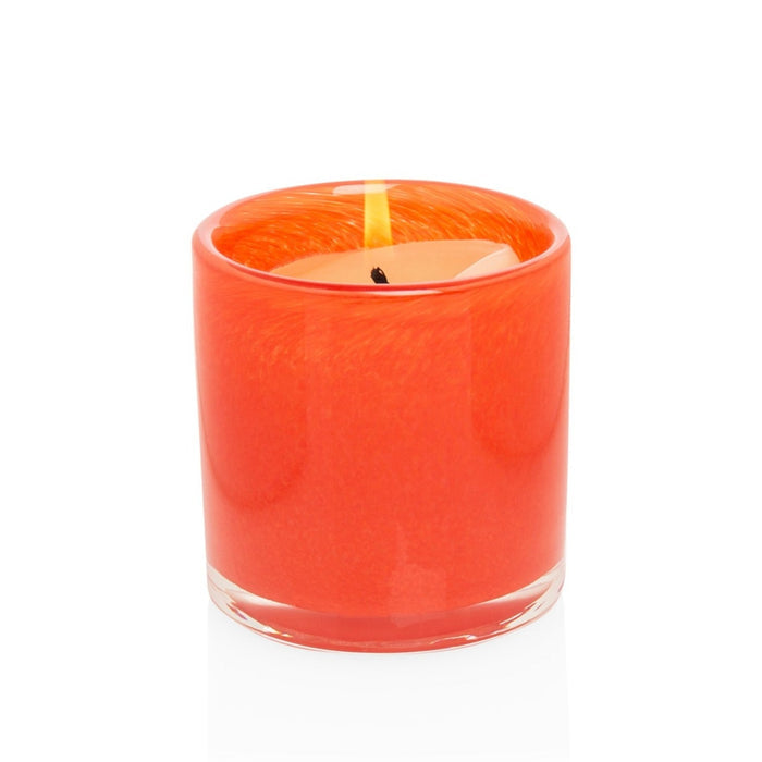 Small orange votive glass candle holder with a lit candle.