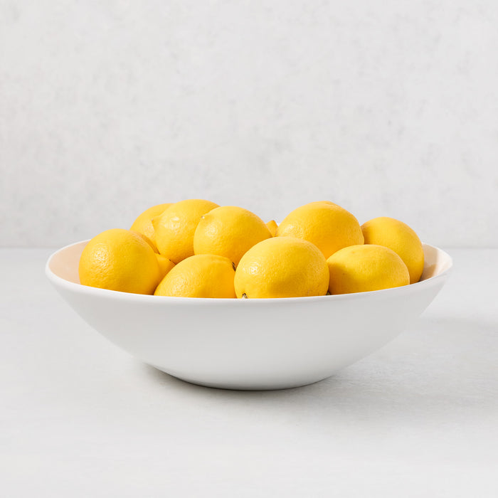 Organic Flared Ceramic Serve Bowl, creamy white, 12" diameter, filled with lemons.