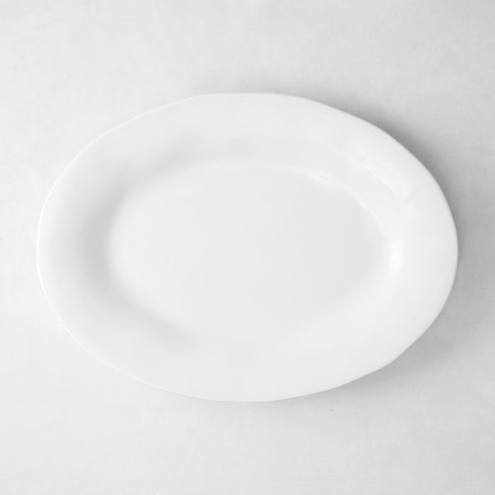 Creamy white oval ceramic serving platter with subtle organic edges.