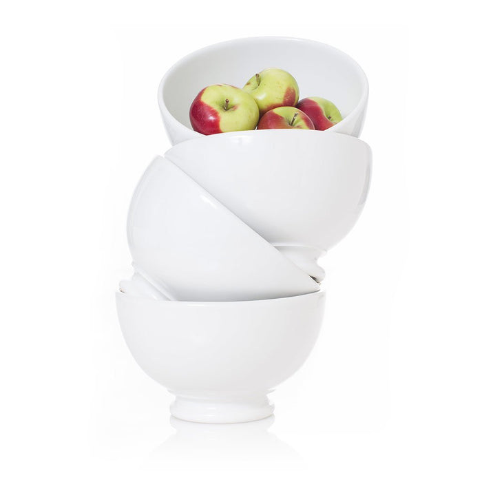 Stack of three creamy white ceramic footed bowls, the top bowl filled with red and green apples.