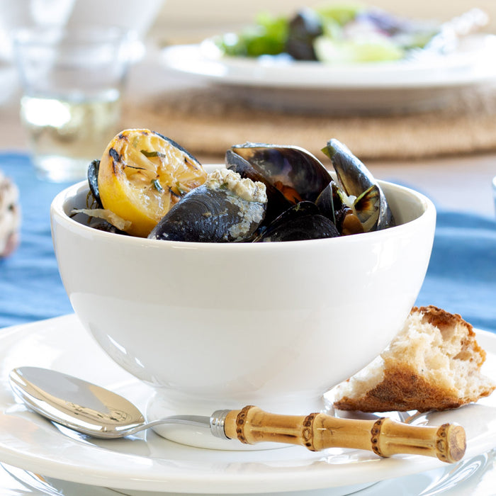 HG Original creamy white ceramic footed bowl filled with mussels and lemon, with bread and cutlery.