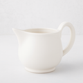 Creamy white ceramic pitcher with a sturdy handle and angled spout.