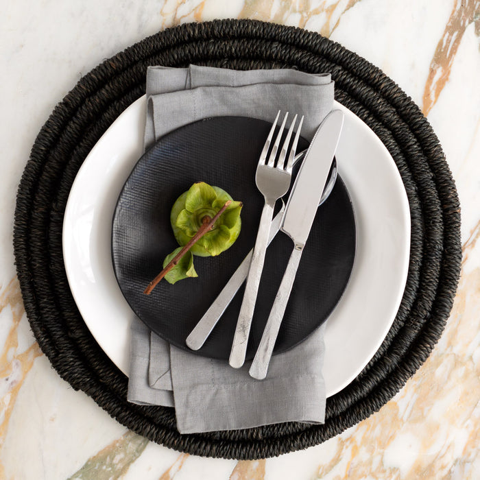 Orleans Stainless 5-Piece Flatware Set with hand-hammered texture on black and white plates.
