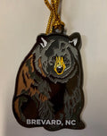 A black bear metal ornament with 'Brevard, NC' text on the bottom side, hanging with a gold string.