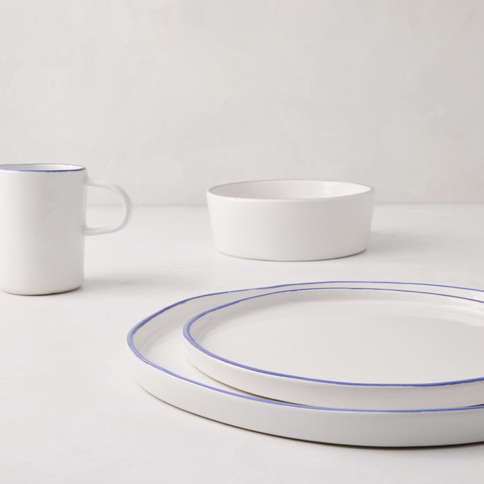 Pacific Blue-Rimmed Stoneware Mug, bowl, and two plates on a white surface.
