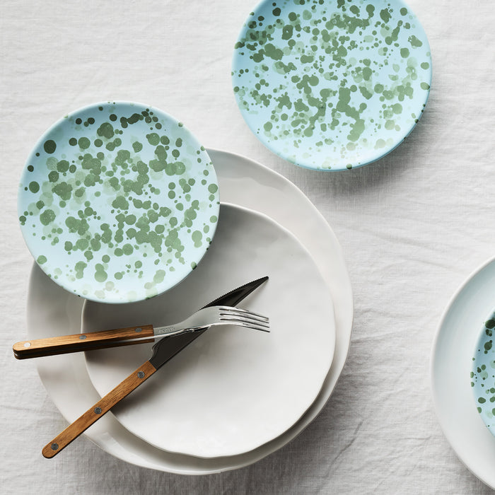 Pebble White ceramic dinner plate with a light blue and green speckled ceramic plate, fork, and knife.